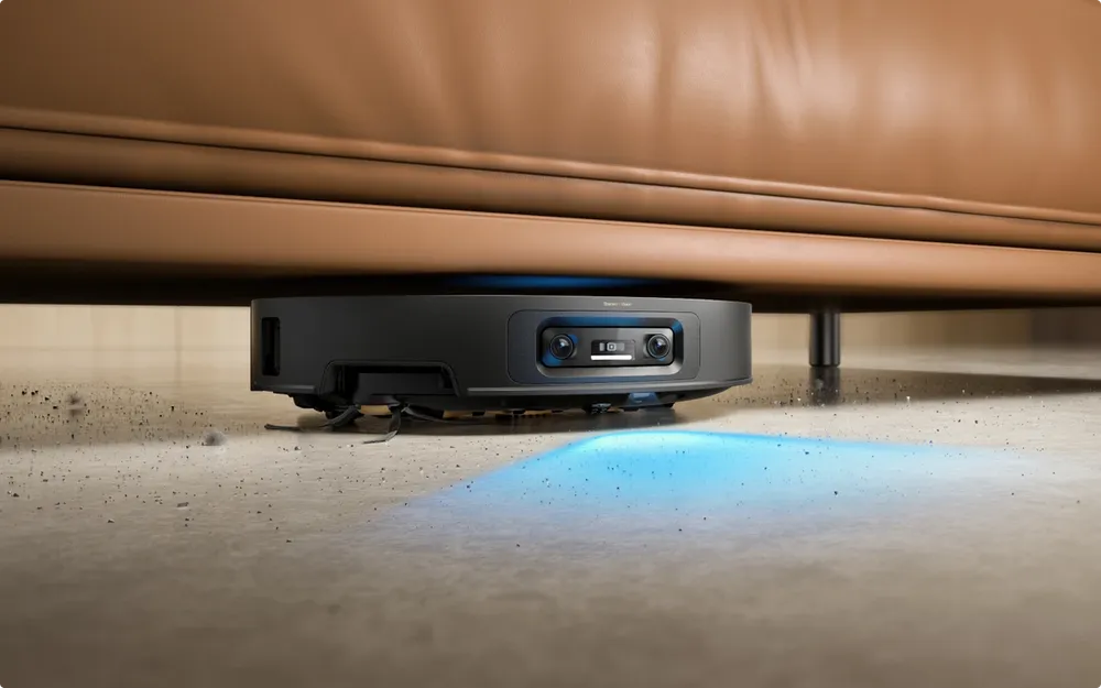 Slim Dreame robot vacuum sliding under a low sofa to reach the dust underneath.