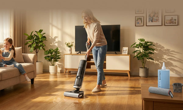 A woman uses a wet dry vacuum to clean a hardwood floor in a bright family living room while a child sits nearby.