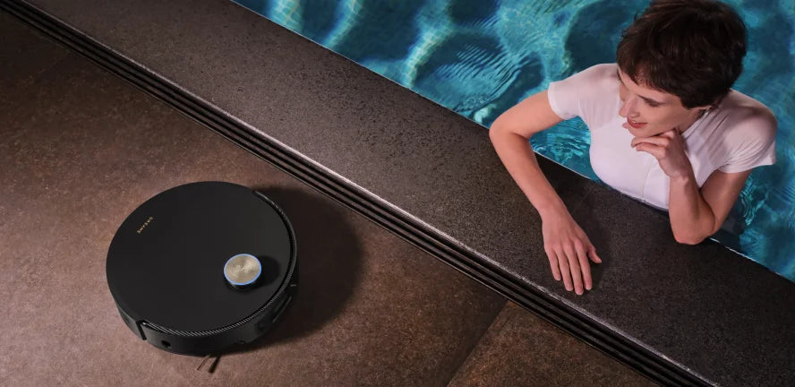 A woman lounges by a pool as Dreame robot mop and vacuum glides along the terrace.