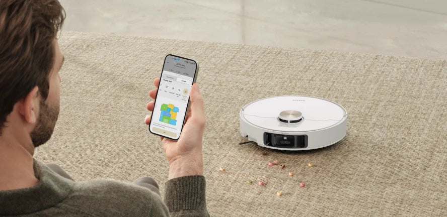 A man uses a mobile app to control Dreame robot mop and vacuum combo to clean the carpet.