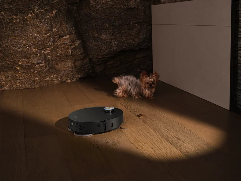 Dreame robot vacuum detecting pet waste on a hardwood floor with a Yorkshire Terrier in the background.